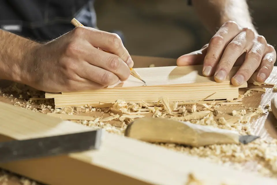 Tischler zeichnet an einem Werkstück an